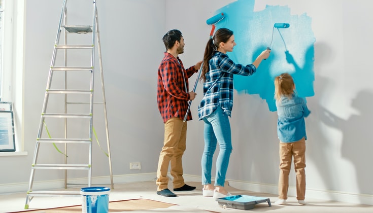 Family painting wall with a Roller. Paint Color is Light Blue