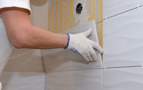 construction work laying tile on the wall close up