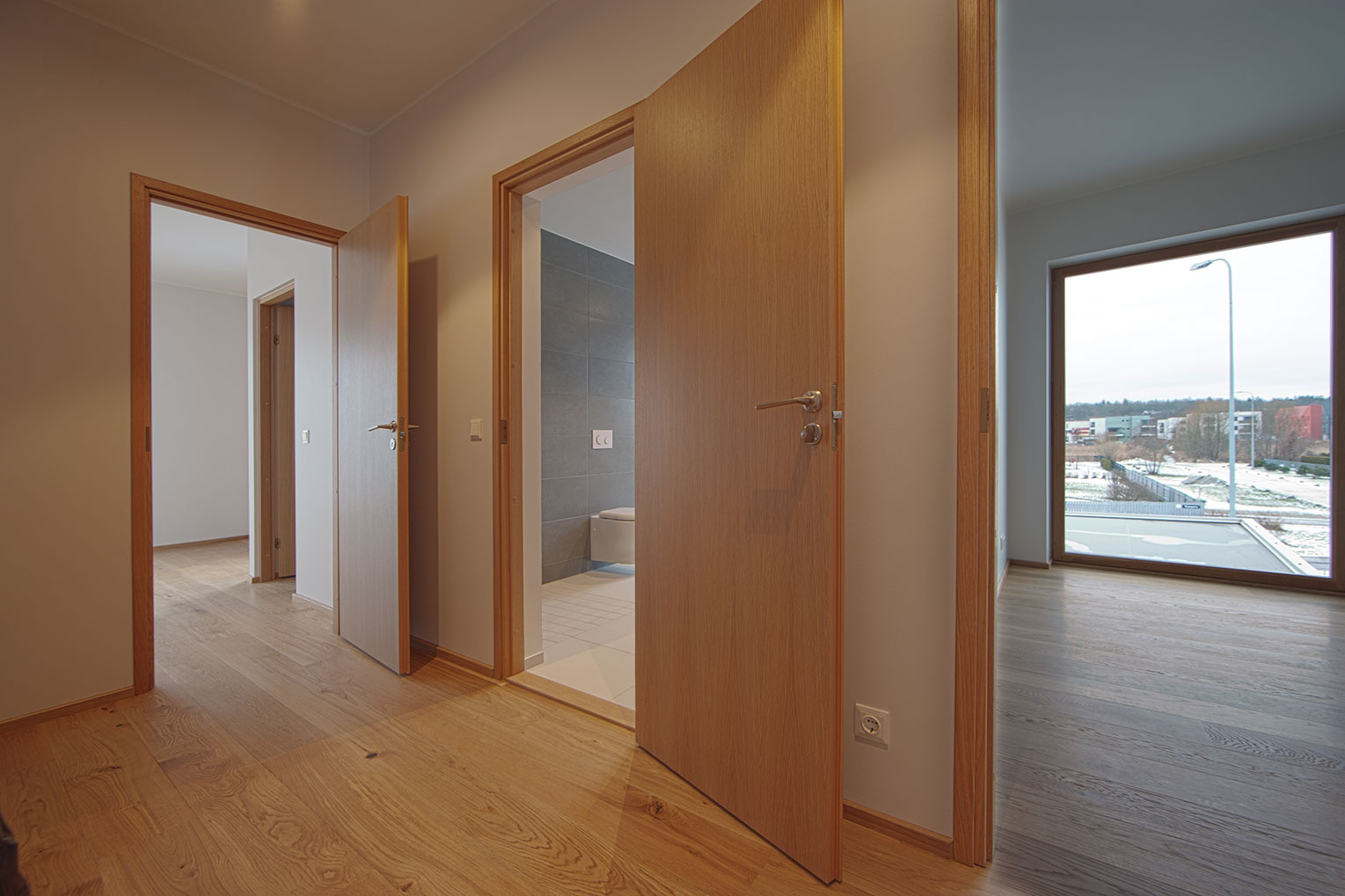 A view from the beige-colored hallway of an apartment that was just renovated and repainted.