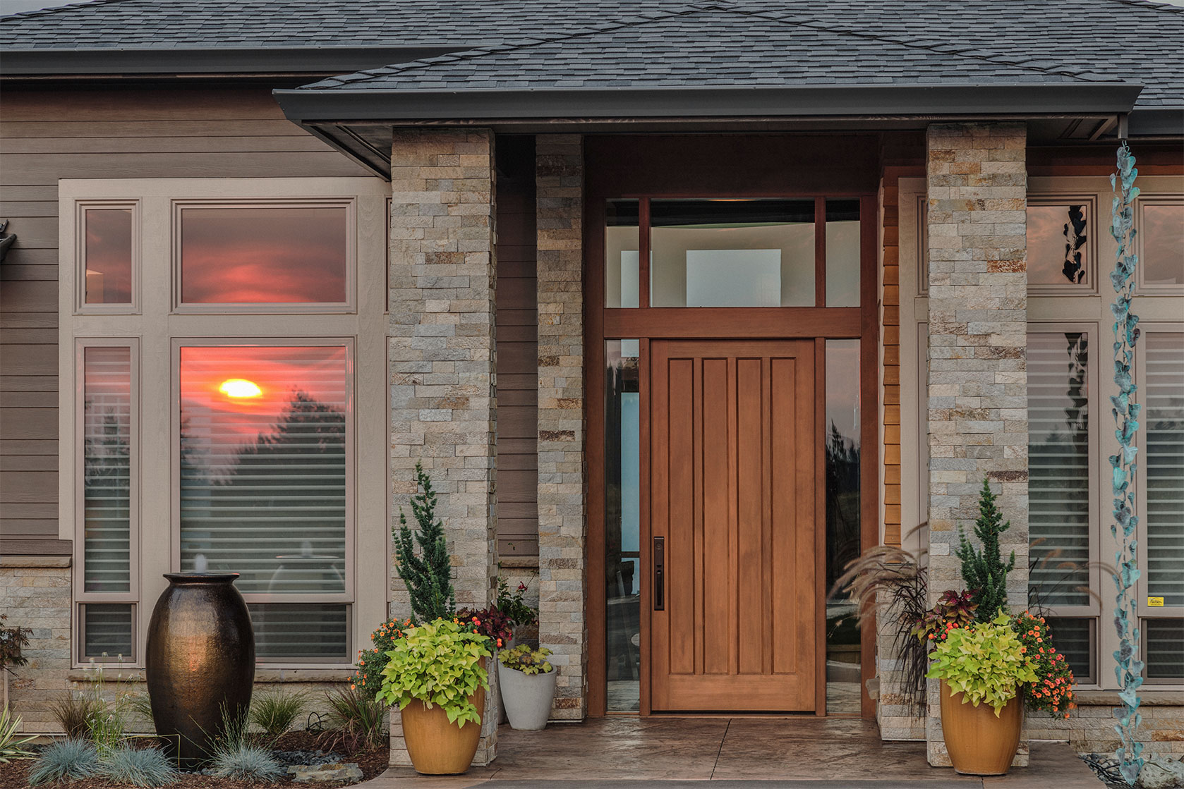 Entrance of a house with light brown painted siding and stained wooden doors. 