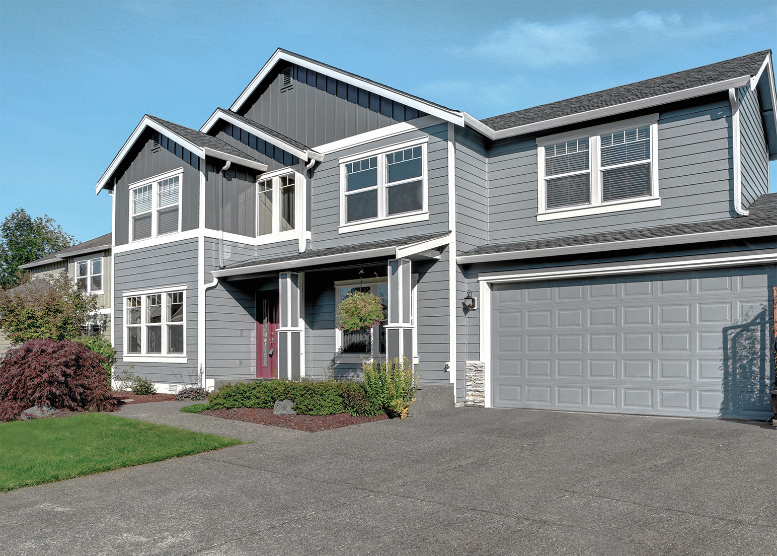 Large two story house with the exterior of the first floor painted a brighter shade of grey than the second.