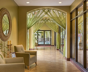 Hotel lobby painting project. The walls are painted yellow to match the beige colored furniture, light green curtains cover the arcs, and the large wood frame windows open a view into the yard.