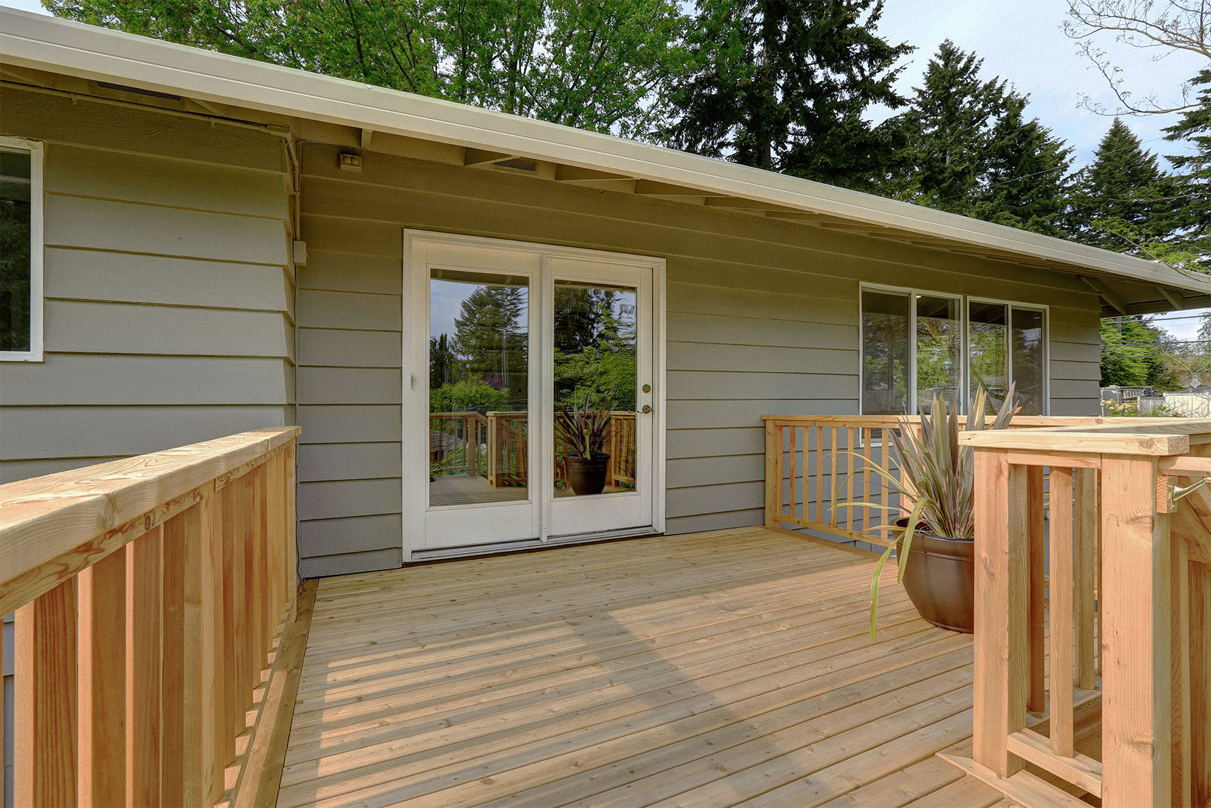 Taupe colored house with a wooden deck.