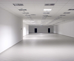 Inside of a large industrial facility. The walls and ceiling are painted white, the floors coated with epoxy.
