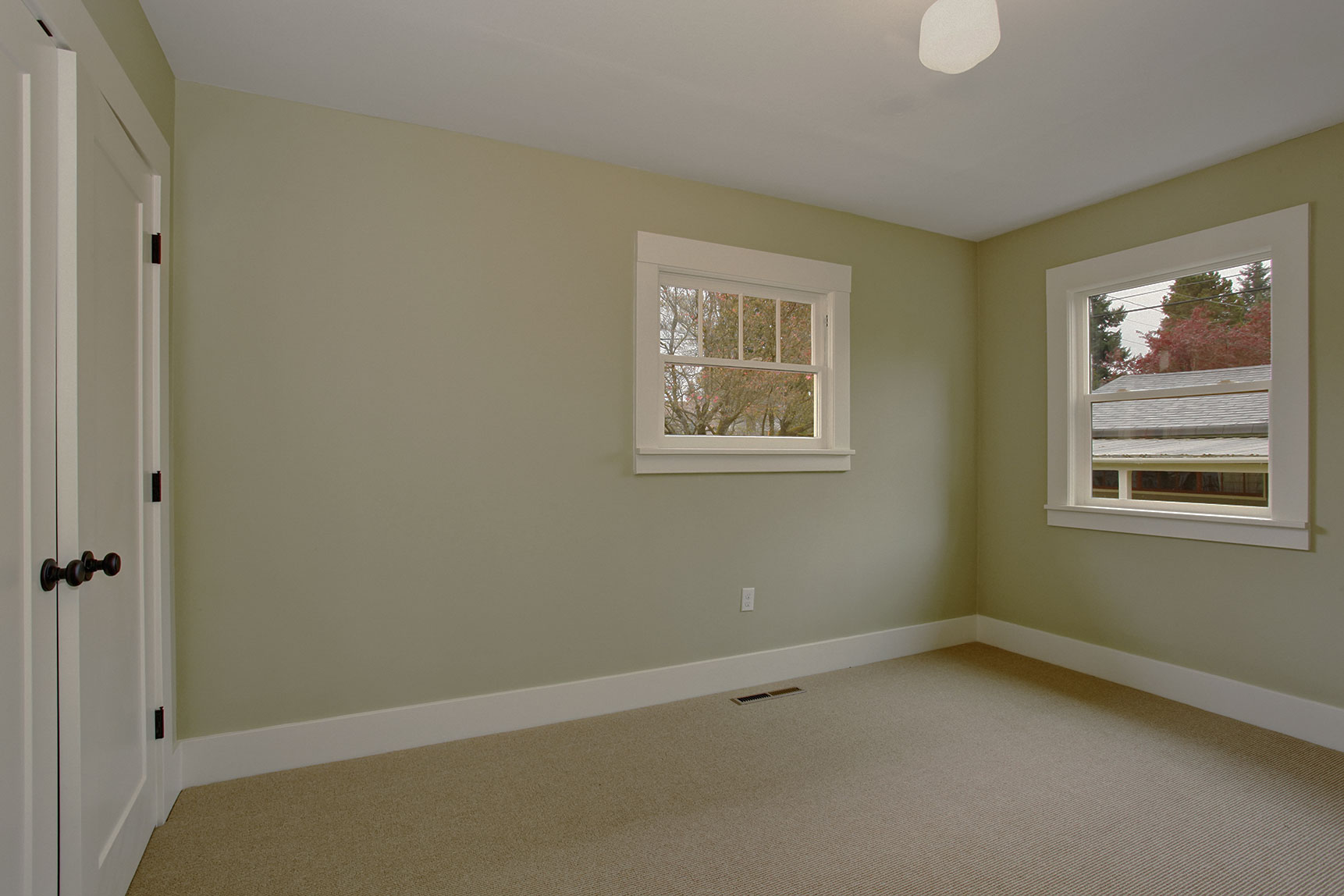 Lauren green painted room with white trim, brown carpet and white doors and windows.