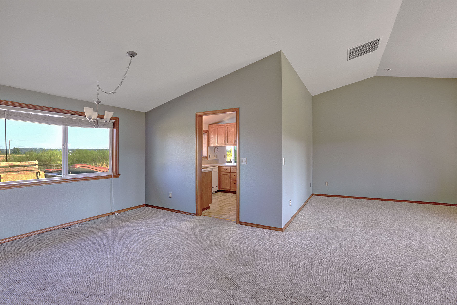 Pastel blue room with a grey carpet and brown trim around the doors, window and floor.