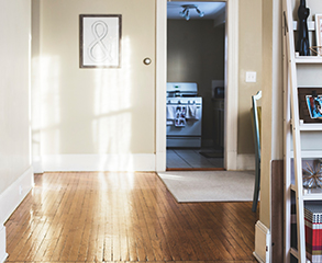 Condo interior with beige walls, white trim and decorations. You can glimpse into the kitchen and see a corner of a bookshelf in the living room.