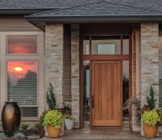 Entrance of a house with light brown painted siding and stained wooden doors. 