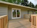 Taupe colored house with a wooden deck.