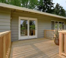 Taupe colored house with a wooden deck.