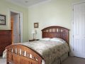 Light green bedroom with dark colored wooden furniture, white doors, two paintings hanging on the walls and white doors. 