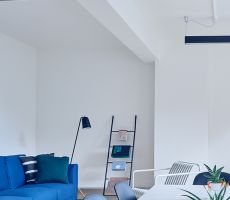 Solid white living room with a teal colored couch and minimalist decor.