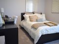 Small bedroom with a black, decorated twin bed, black desk with white and gold colored decorations on top and a white chair next to it, gray carpet and gray painted walls. 