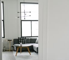 White interior of loft in Chicago, with large dark framed windows, grey couch and a coffee table in the center of the room.